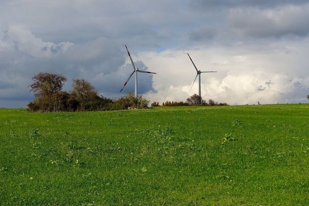 Zwei Windräder im Offenland mit bewölktem Himmel