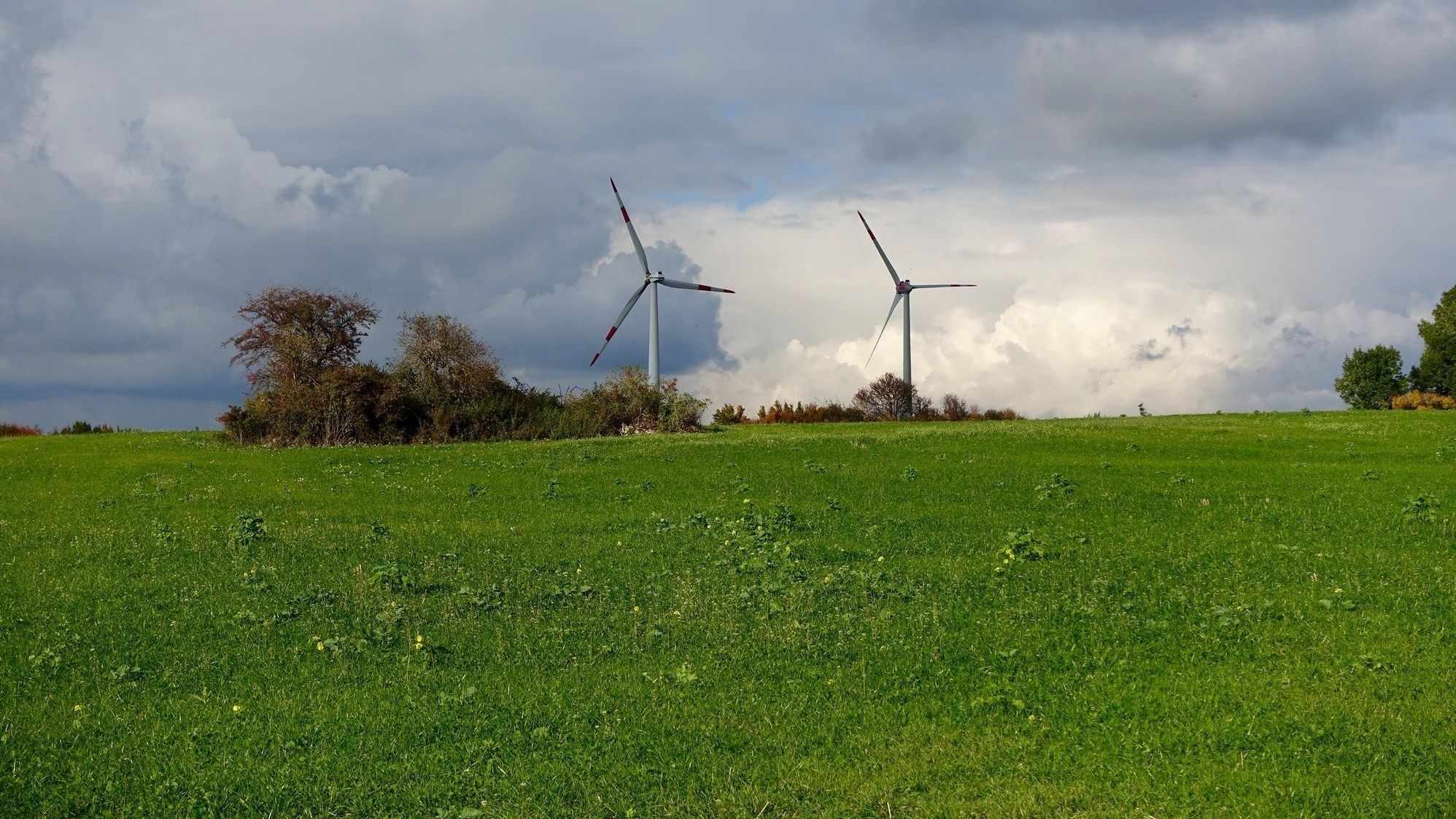 Zwei Windräder im Offenland mit bewölktem Himmel